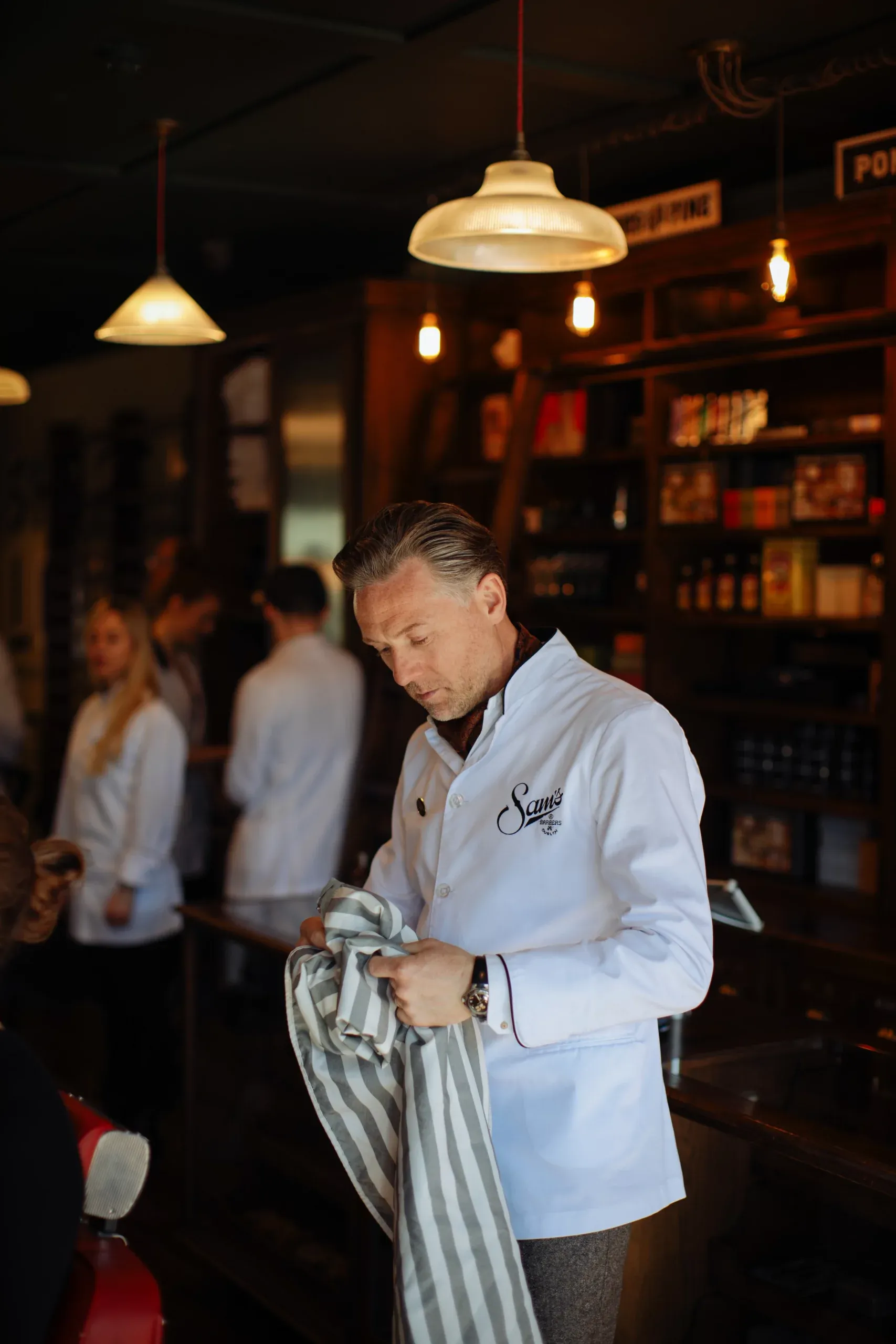 A Sam's barber folding a striped towel